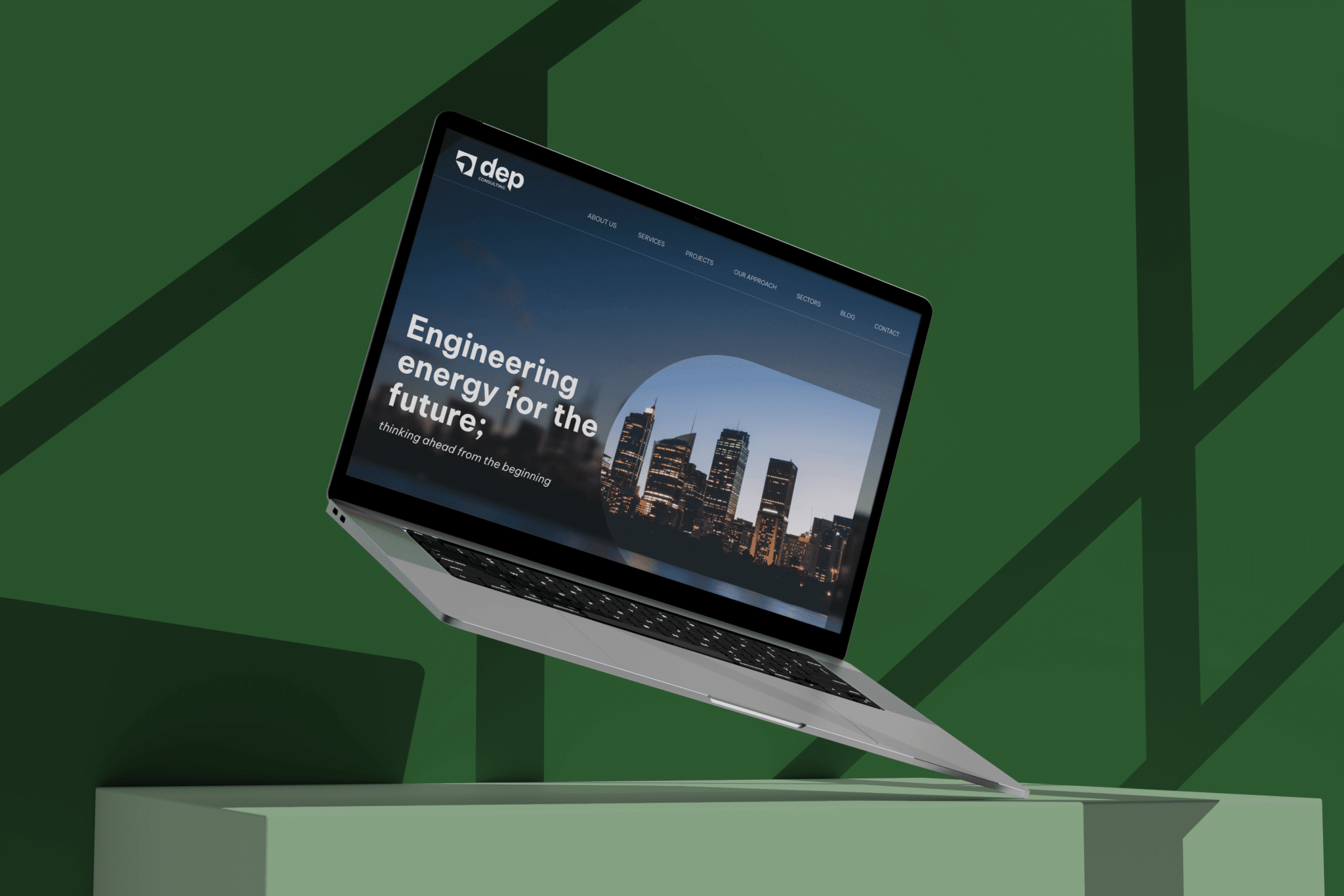 Laptop on a green stand displaying a corporate website with a city skyline at night, captioned "engineering energy for the future.