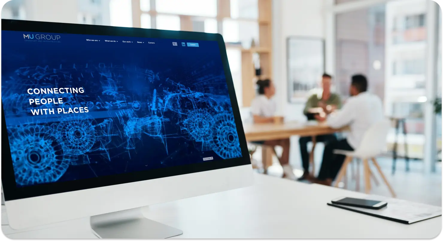 A computer screen showcases a digital design with the text "Connecting People with Places," highlighting a WordPress website. In the background, four people are having a meeting in a modern office space, brainstorming ideas for innovative website development.