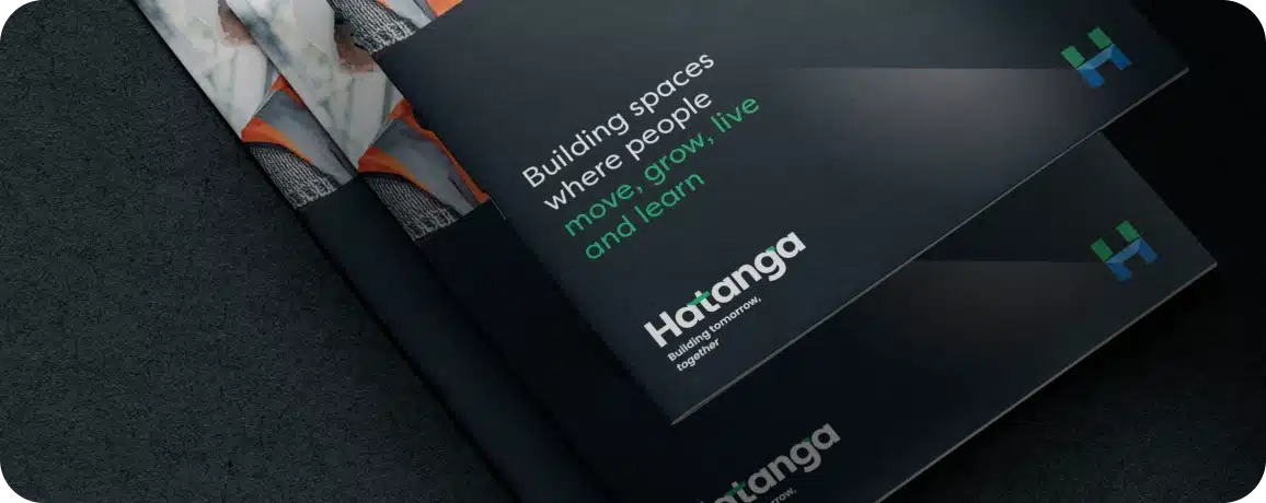 Stacked dark brochures with "Building spaces where people move, grow, live and learn" in white and green text, showcasing Hatanga's expertise. The branding highlights their strength as an agency at the forefront of innovative construction.