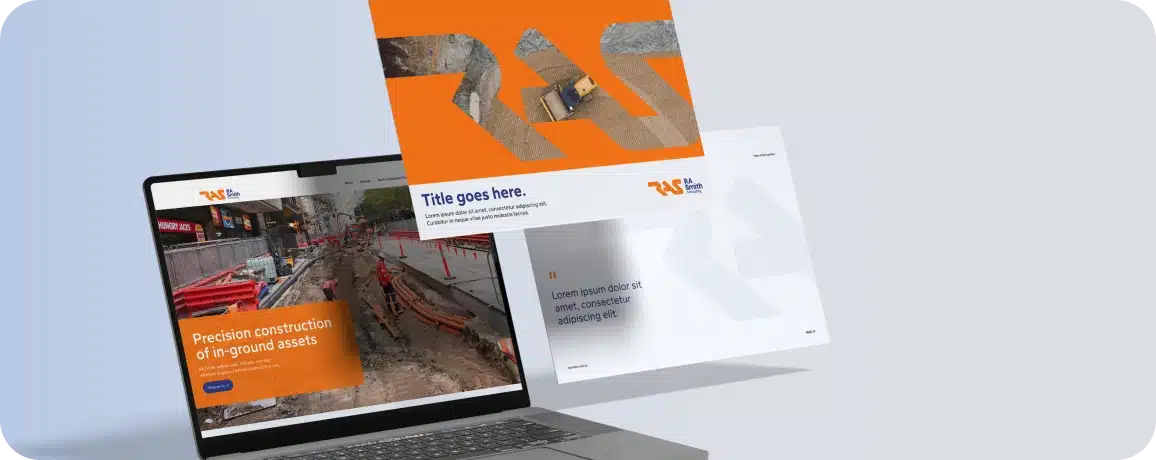 A laptop showcases a construction agency's website, accompanied by two brochures displaying vivid construction images and branding elements.