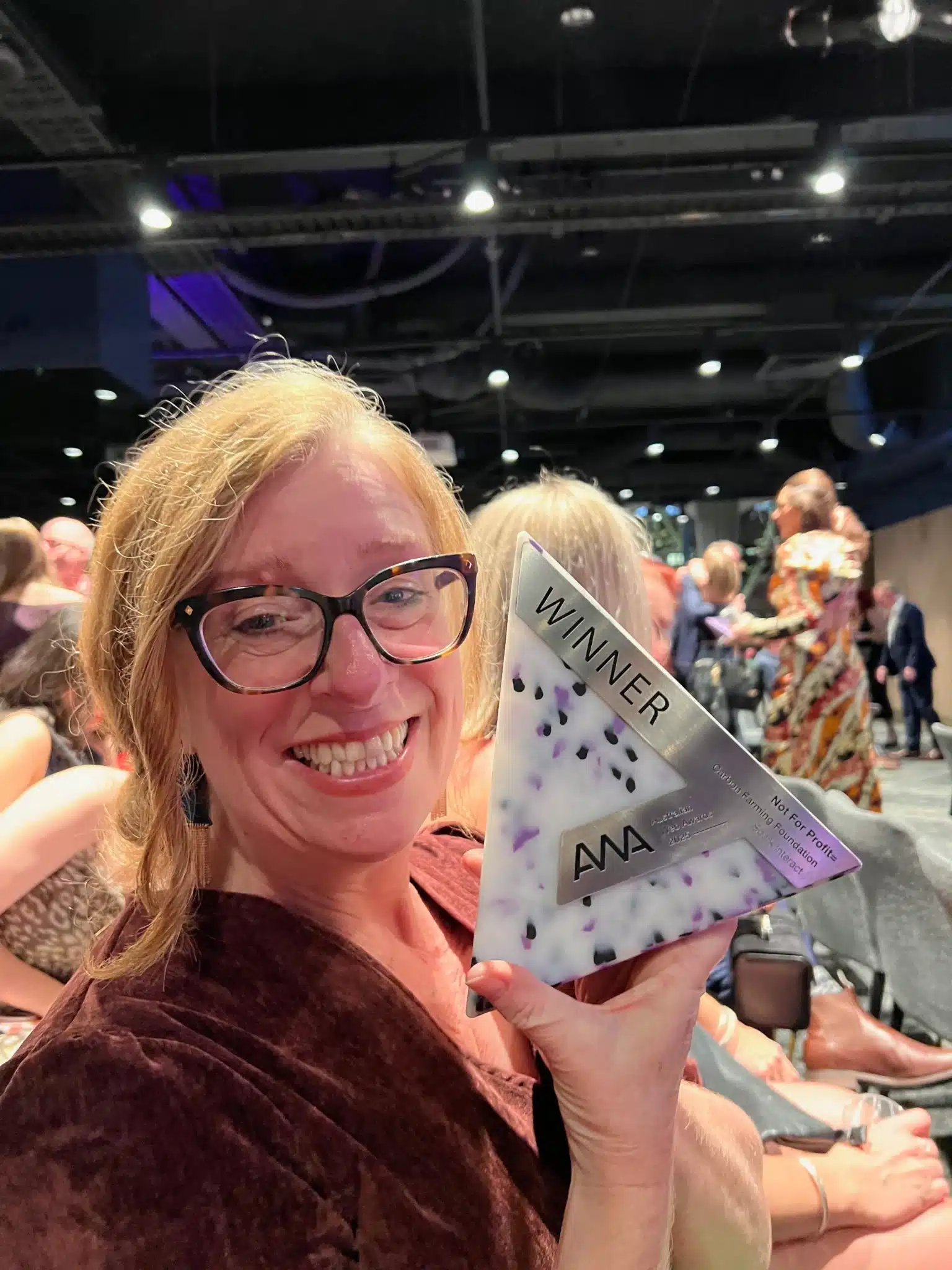 Katherine Norris, Creative Director at Spark Interact holds up the Australian Web Awards trophy won at 2025 Awards Night.