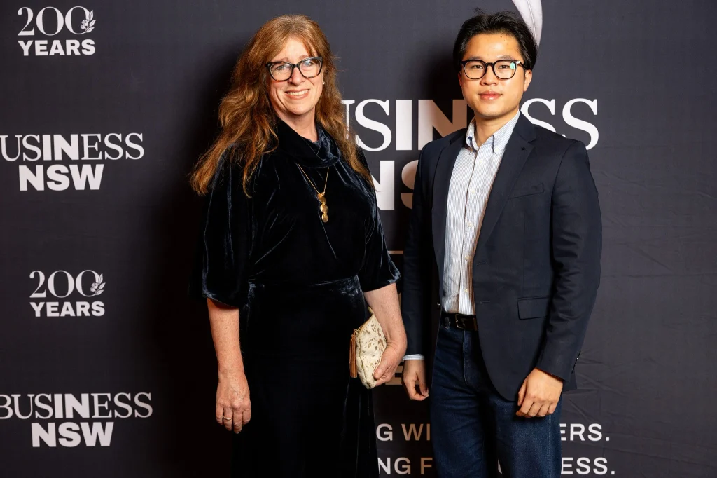 Two people stand side by side in business attire, posing for a photo in front of a “Business NSW 200 Years” event backdrop, highlighting the brand recognition of the prestigious milestone.